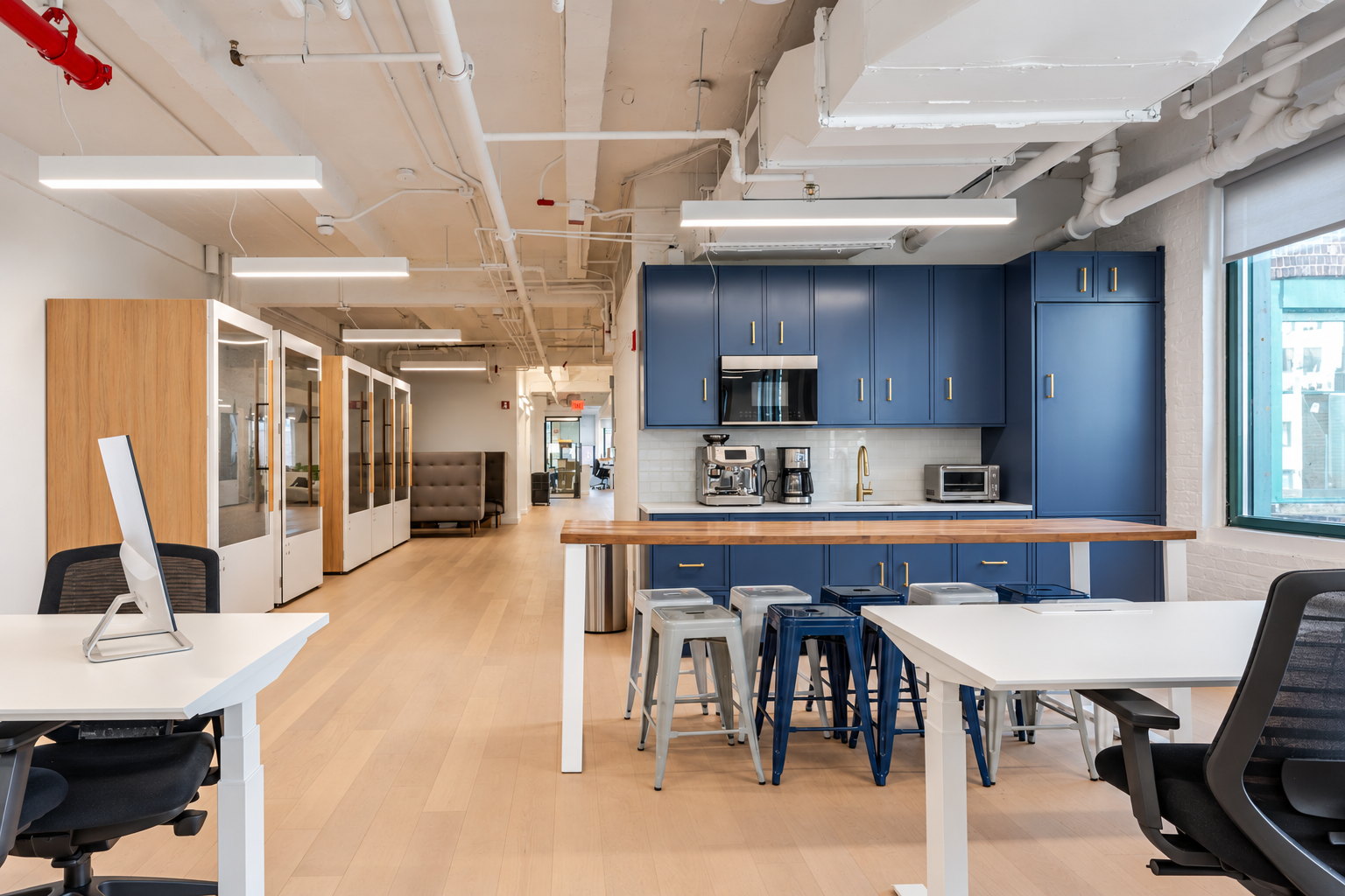 Seventh floor pantry with full-height cabinetry, an island with stools, and phone booths beyond